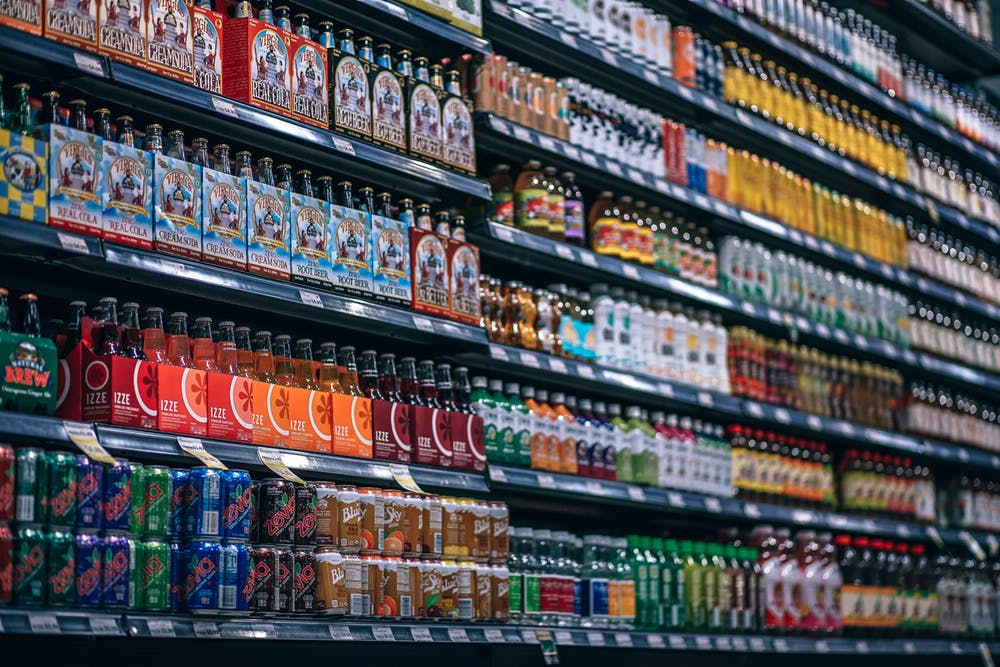 bottles and cans lined up on supermarket shelves